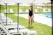 © rh2010 - Young woman in black swimsuit standing with cocktail at the swimming pool area during summer vacations