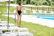 © rh2010 - Young woman in black swimsuit standing with cocktail at the swimming pool area during summer vacations