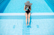 © rh2010 - Young woman in black swimsuit and sun hat relaxing with cocktail in the swimming pool outdoors