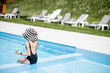 © rh2010 - Young woman in black swimsuit and sun hat sitting back with cocktail in the swimming pool outdoors