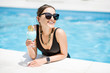 © rh2010 - Portrait of a beautiful woman in black swimsuit relaxing with cocktail at the swimming pool outdoors