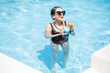 © rh2010 - Beautiful woman in black swimsuit and sunglasses swimming with cocktail in the water pool outdoors