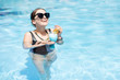 © rh2010 - Beautiful woman in black swimsuit and sunglasses swimming with cocktail in the water pool outdoors