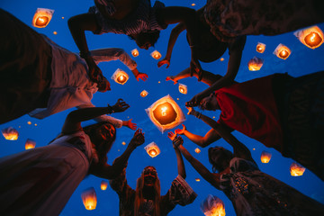 Group of friends making party on the beach at sunset time