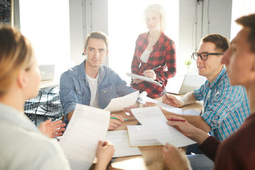 Canvas Print - Group of young financiers listening to report of colleague and her explanation of its main points