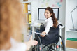 © pressmaster - Disable manager in wheelchair passing paper to her colleague in office