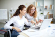 © pressmaster - Happy woman in wheelchair pointing at laptop display while explaining online data to colleague at meeting