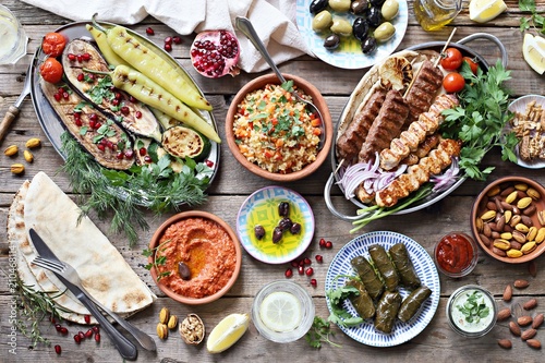 Cuadros en Lienzo Middle eastern, arabic or mediterranean dinner table with grilled lamb kebab, chicken skewers with roasted vegetables and appetizers variety serving on wooden outdoor table