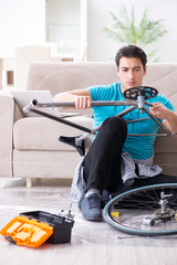 Young man repairing bicycle at home