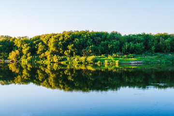 Wall Mural - Summer nature panorama, forest trees and river with reflection in water, abstract vivid tranquil and relax background