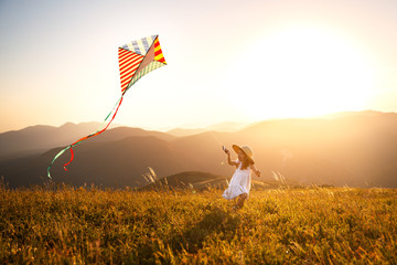 Wall Mural - happy child girl running with kite at sunset outdoors