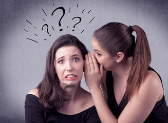 Wall Mural - A teenager girl looking confused with drawn question marks above the head, while a girlfriend whispers something in her ear concept.