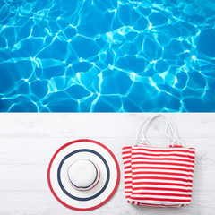 Summer accessories hat and bag on white wooden background.