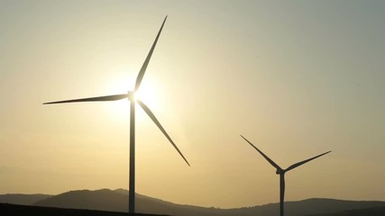 Wall Mural - wind turbines blades rotation in motion in beautiful summer day with bright sunlight and mountain area on background clear sky nobody outside converting wind energy electrical engineering equipment