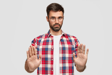 Wall Mural - Pleasant looking serious male office worker refuses to help with preparing project, shows stop gesture, asks not bother him during vacation, has thick beard and mustache, isolated on white wall