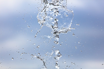 Splashing water with drops on the sky background