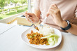 © zasabe - Asian girl eating lunch on the table. The food that is eaten in Thailand is called fried pork loin. Spicy and hot Fast food concept, healthy concept, Thai food, Asian food.
