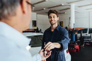 mechanic giving car keys to customer after servicing