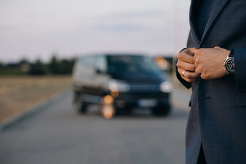 man in suit stay in front of luxury car minivan