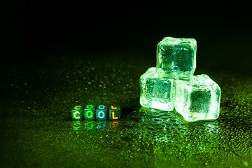 Green ice cubes reflection on black table.