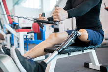 Low Section Closeup Of Unrecognizable Muscular Man With Prosthetic Leg Using Weight Machines While Working Out  In Gym, Copy Space