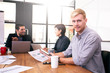 © Jestercine - Businessman looking to camera with attractive smile. People working at office place together.