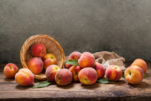Peaches With Leaves In A Basket On Wooden Table