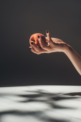 Wall Mural - partial view of woman holding ripe peach in hand on black background