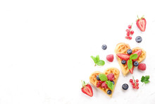 Heart Shape Belgium Waffles With Assorted Berries Mix, Strawberry, Blueberry, Raspberry And Red Currant Decorated With Mint Leaf On White Ceramic Plate. Close Up, Copy Space, Background, Top View.