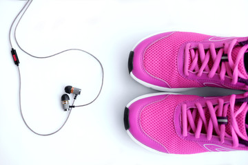 Pink running shoes for women and headphones on a white background