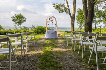 wedding decoration of white chairs, arc of flowers awaits its bridegroom. beautiful sea scenery, lit torches and charming decoration for a wonderful wedding.