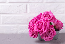 Bright Pink Roses Flowers  On Grey Background Against White Wall.