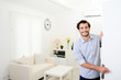 © W PRODUCTION - handsome young man welcome friends at open front door new student home apartment