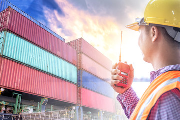 Engineer holding radio communication and container on shipping boat background