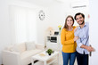© W PRODUCTION - cheerful young couple man and woman welcome friends at open front door new student home apartment