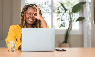 Sticker - African american woman with laptop with happy face smiling doing ok sign with hand on eye looking through fingers