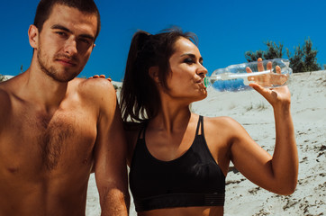 two athletes, a boy and a girl, play sports on the beach. guy black girl Asian . cyclists resting. drink water