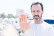 © Krakenimages.com - Handsome middle age man in marina with open hand doing stop sign with serious and confident expression, defense gesture