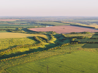 Aerial view of nature landscape panorama from above, summer green fields in rural area, countryside villages and farm meadows at sunset time