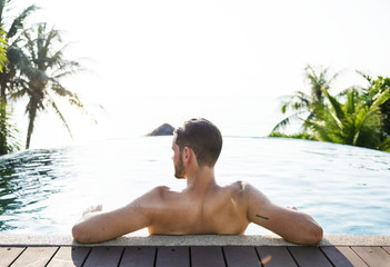 Rear view of man relaxing in a pool