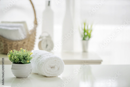 Fotografiet Roll up of white towels on white table with copy space on blurred living room ba