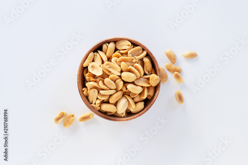 Fotografía Roasted salted peanuts in wooden bowl on white background.
