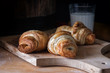 Fresh cooked croissants close up on cutting board next to glass with milk. fresh pastry, bakery.