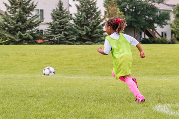 Wall Mural - A young girl is learning how to play soccer