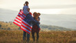 © JenkoAtaman - happy family with flag of america USA at sunset outdoors.