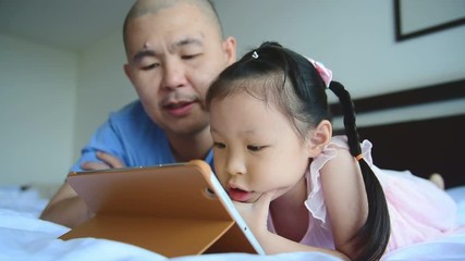 Wall Mural - Asian father and daughter using tablet computer on bed
