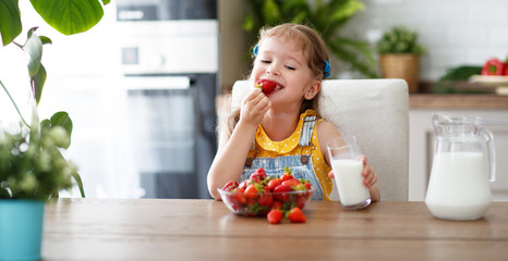 Wall Mural - happy child girl eating strawberries with milk  .