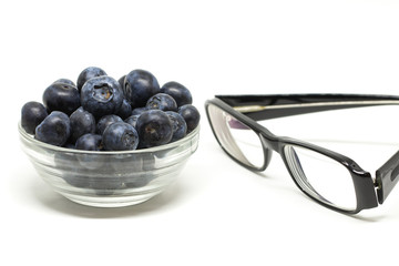 Bilberry transparent bowl on the white background. Cure for eyes concept with glasses