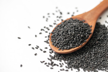 black sesame seeds in wooden spoon on white background