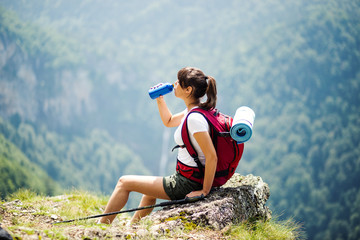 female tourist with backpack drinking water.woman resting with water bottle during hike